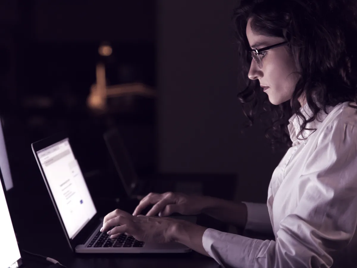 Mulher pesquisando no notebook em um escritório à noite