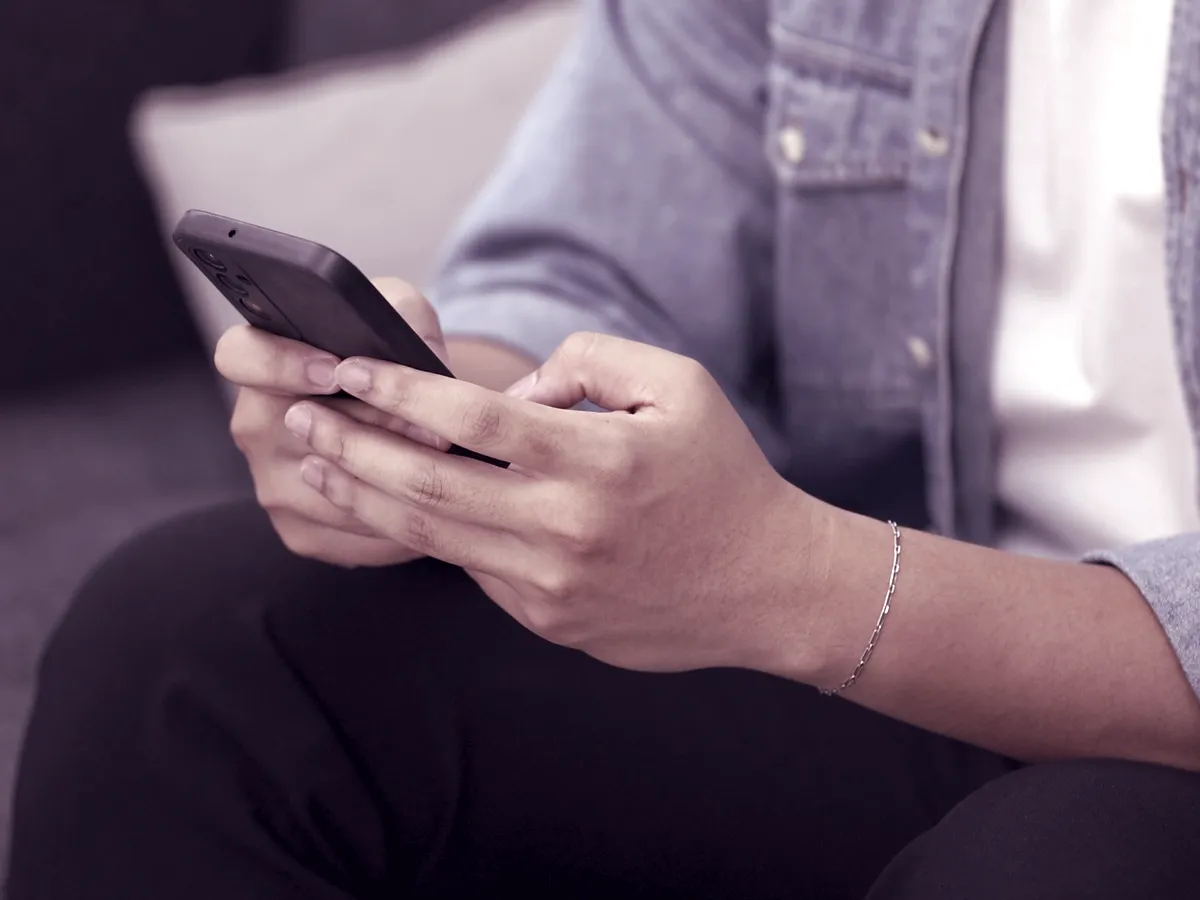 Mãos digitando uma pergunta no celular